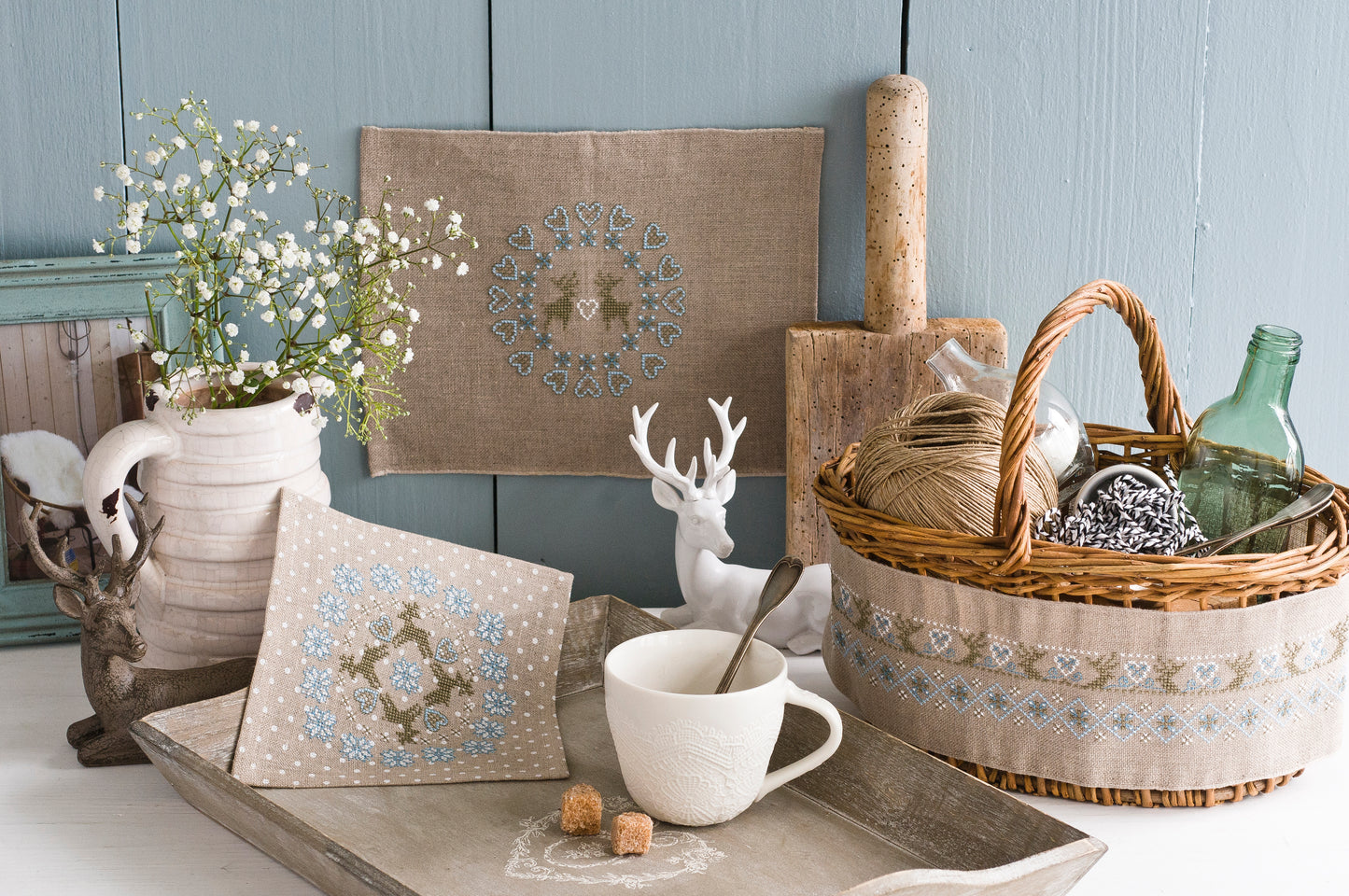 Frises et motifs géométriques nordiques brodés sur lin naturel ou gris perlé, signés M.A. Réthoret-Melin. Cœurs, cerfs et motifs folkloriques en bleu et brun.