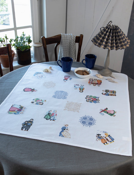 Grille de broderie point de croix « Nappe Bretagne » par M. Bonnin : personnages en costume breton et bigoudènes sur toile blanche 5,5 pts. DMC, 6 pages, motif 11 x 11 cm.