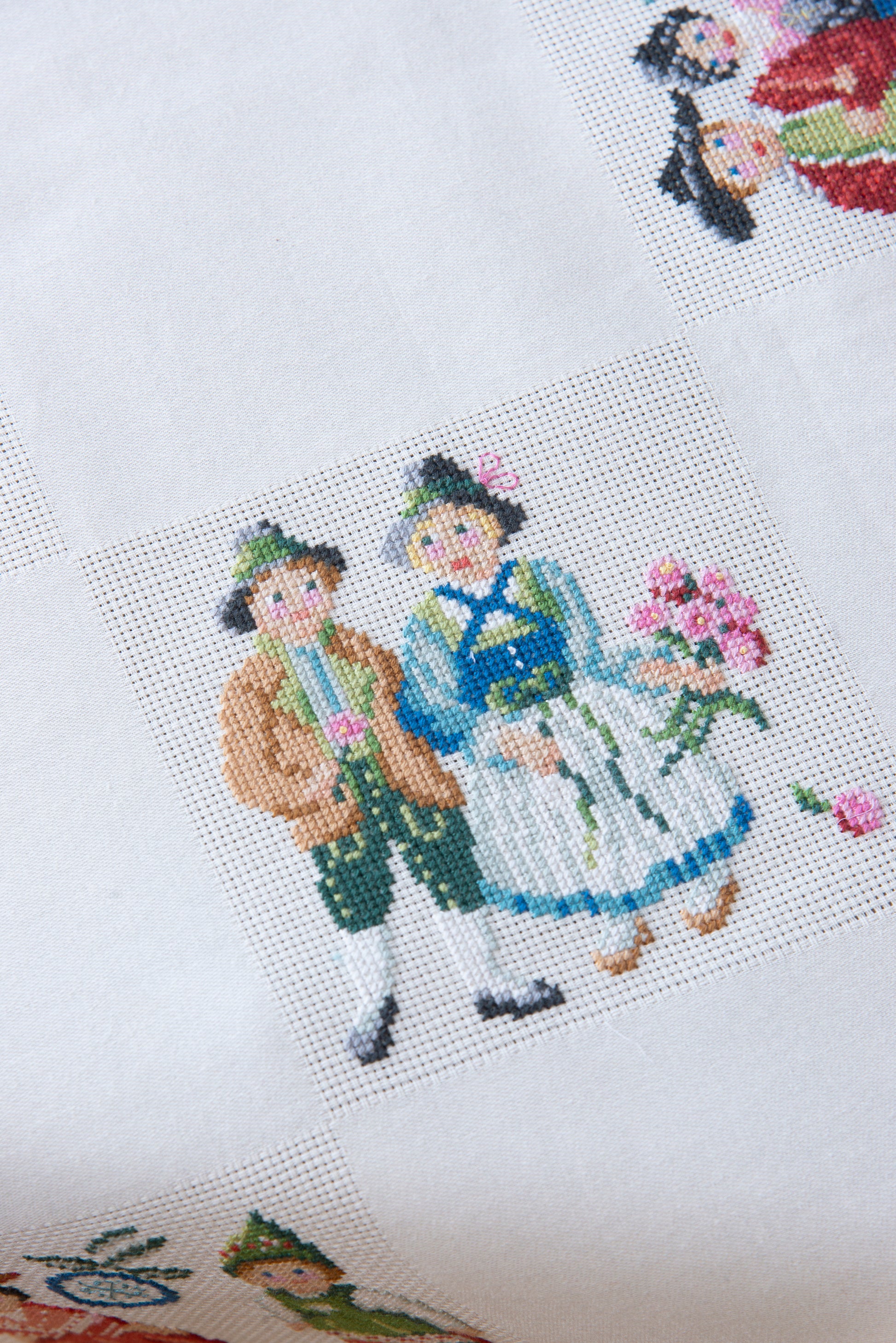 Grille de broderie point de croix « Nappe Tyrol » par M. Bonnin : personnages en costume tyrolien sur Aïda blanc 5,5 pts. DMC, 6 pages, motif 12,36 x 12,36 cm.