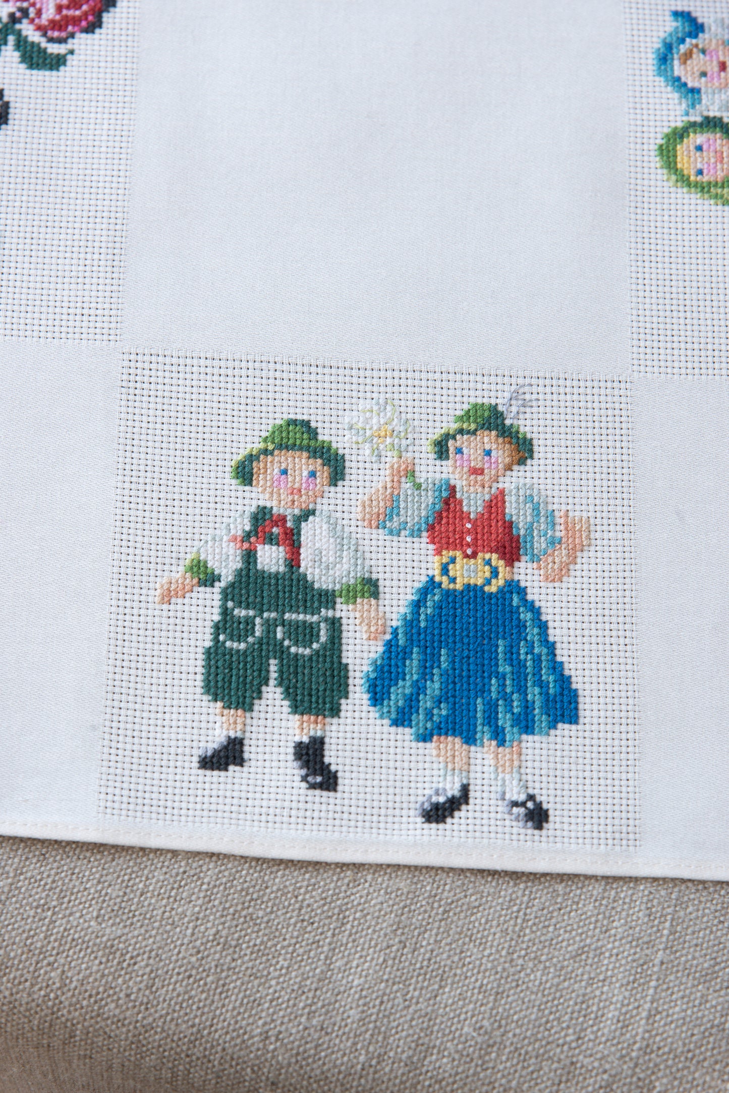 Grille de broderie point de croix « Nappe Tyrol » par M. Bonnin : personnages en costume tyrolien sur Aïda blanc 5,5 pts. DMC, 6 pages, motif 12,36 x 12,36 cm.