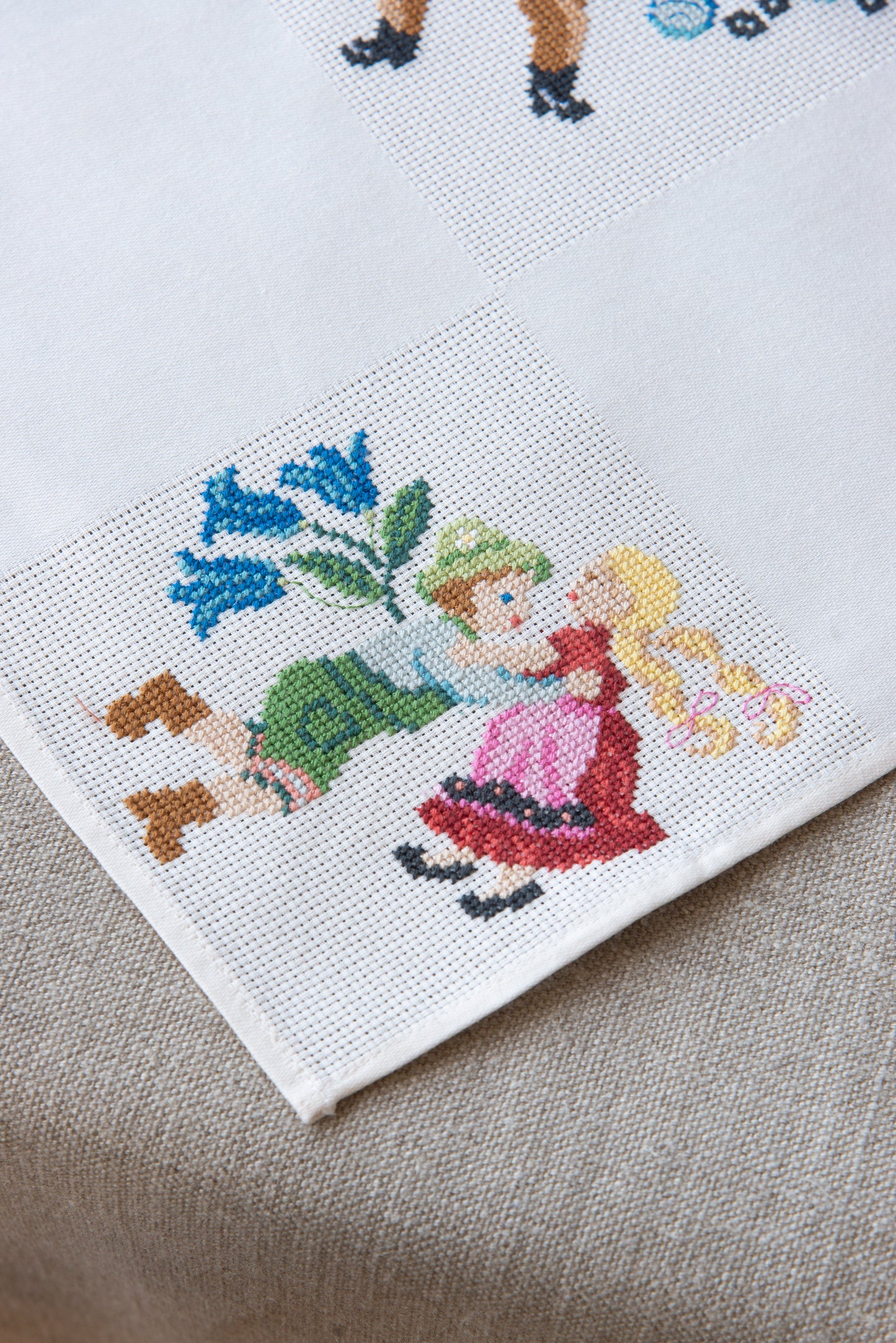 Grille de broderie point de croix « Nappe Tyrol » par M. Bonnin : personnages en costume tyrolien sur Aïda blanc 5,5 pts. DMC, 6 pages, motif 12,36 x 12,36 cm.