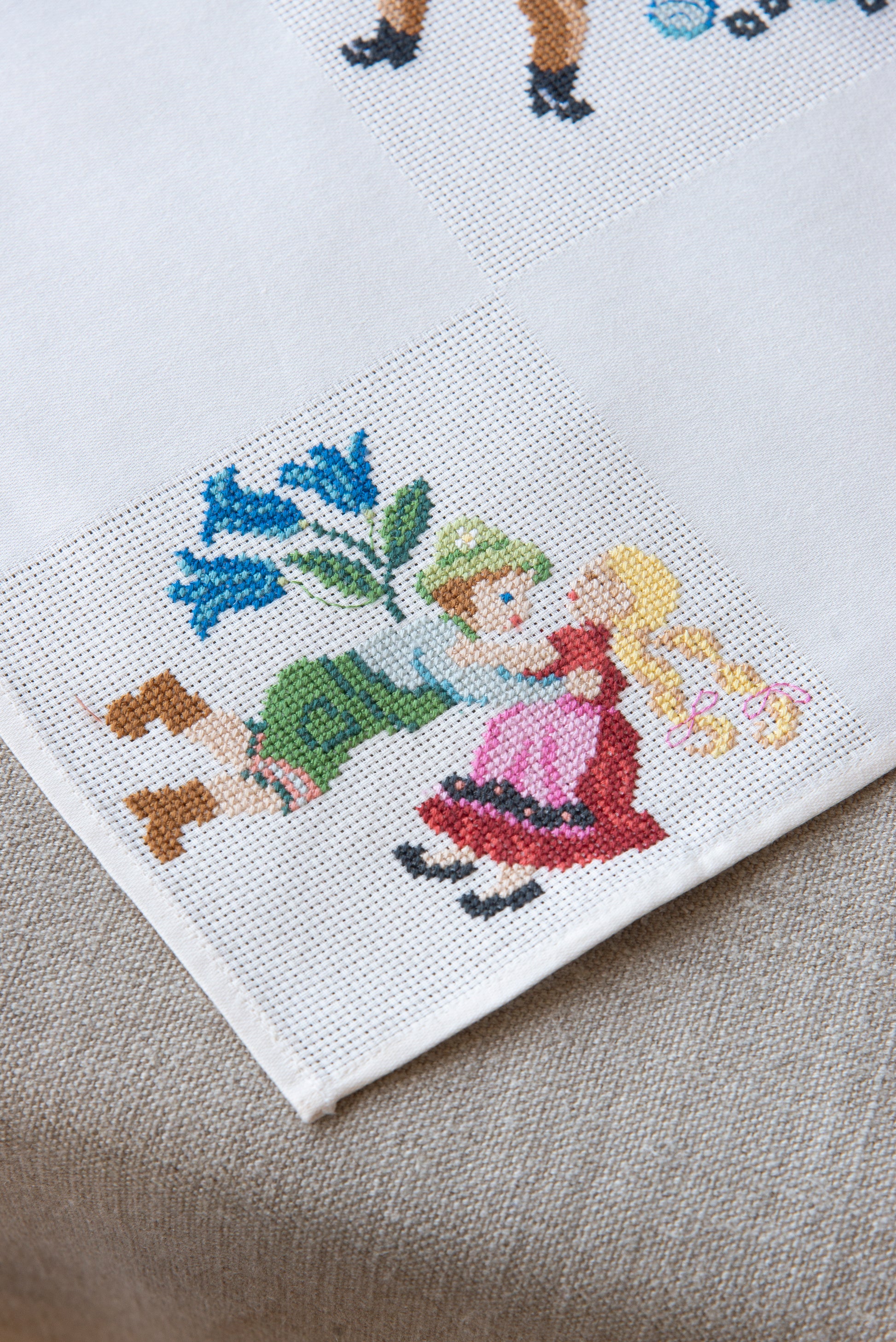 Grille de broderie point de croix « Nappe Tyrol » par M. Bonnin : personnages en costume tyrolien sur Aïda blanc 5,5 pts. DMC, 6 pages, motif 12,36 x 12,36 cm.