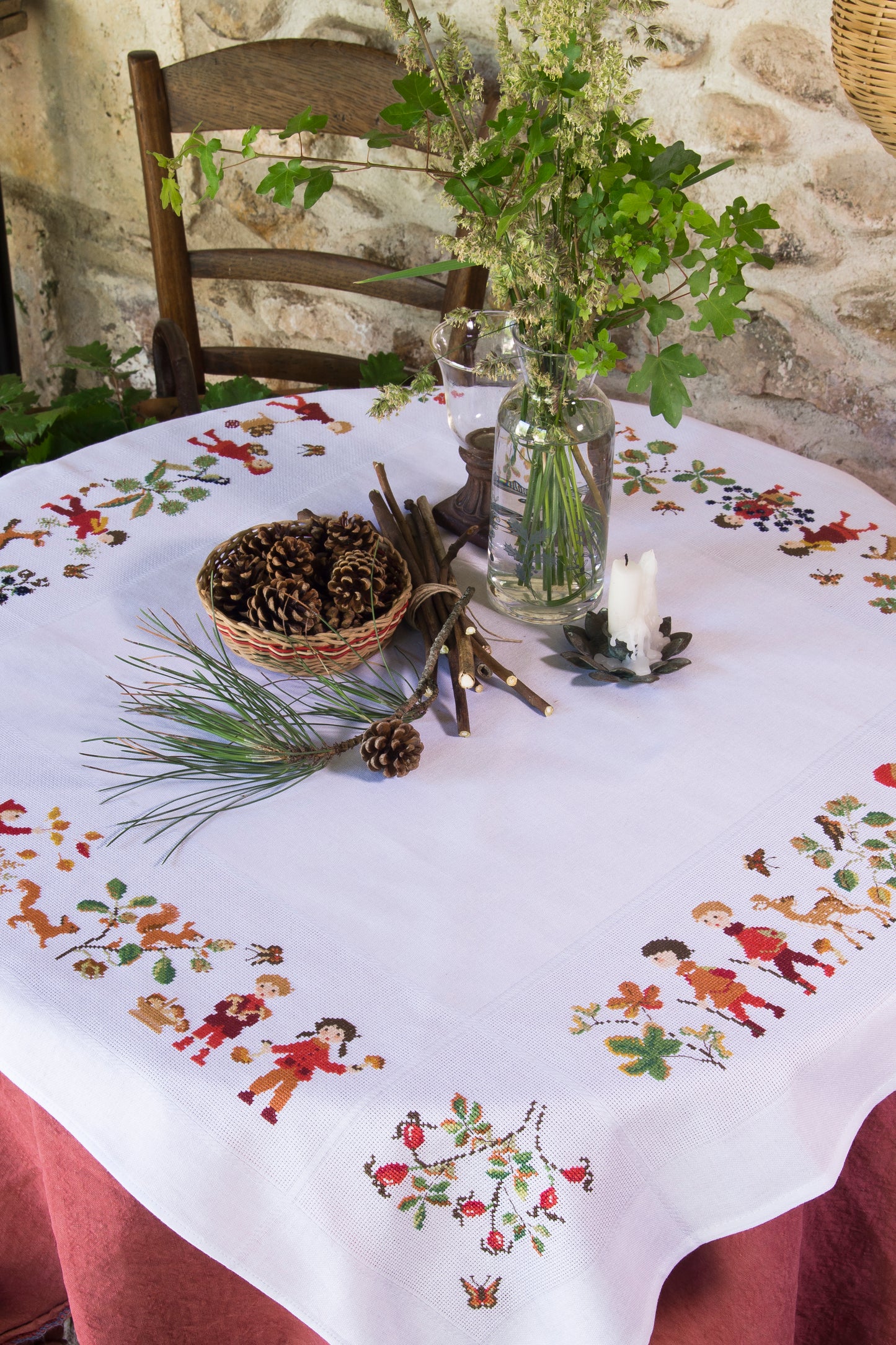 Grille point de croix : nappe d’automne à broder sur toile blanche 5,5 pts. Feuilles, fruits et personnages. 12 pages DMC. Linge de table automnal.