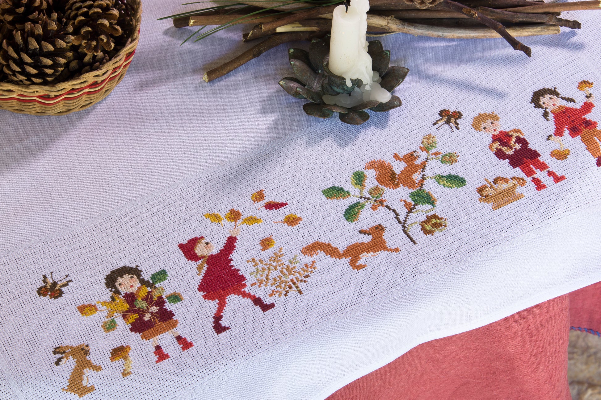 Grille point de croix : nappe d’automne à broder sur toile blanche 5,5 pts. Feuilles, fruits et personnages. 12 pages DMC. Linge de table automnal.