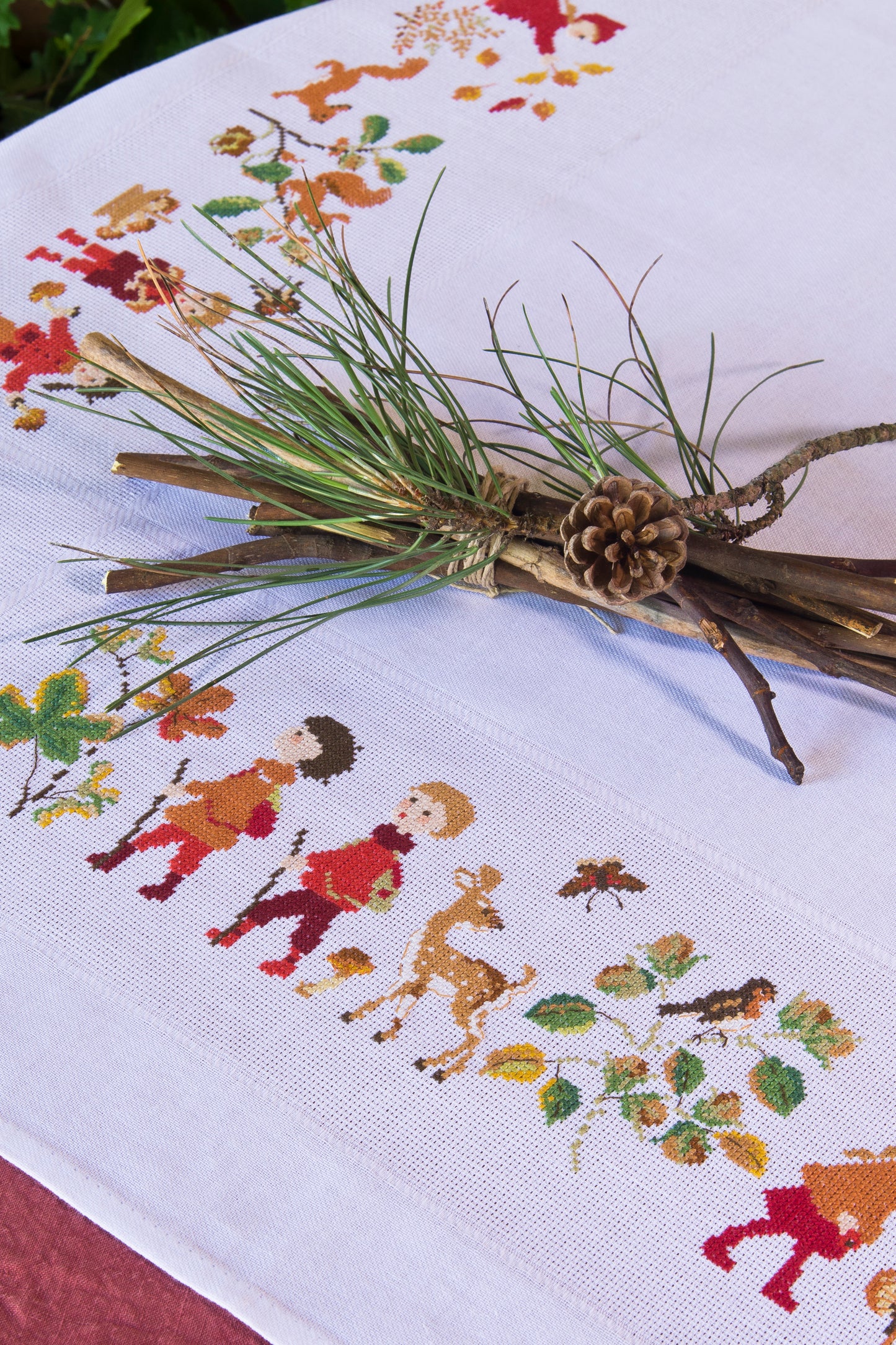 Grille point de croix : nappe d’automne à broder sur toile blanche 5,5 pts. Feuilles, fruits et personnages. 12 pages DMC. Linge de table automnal.