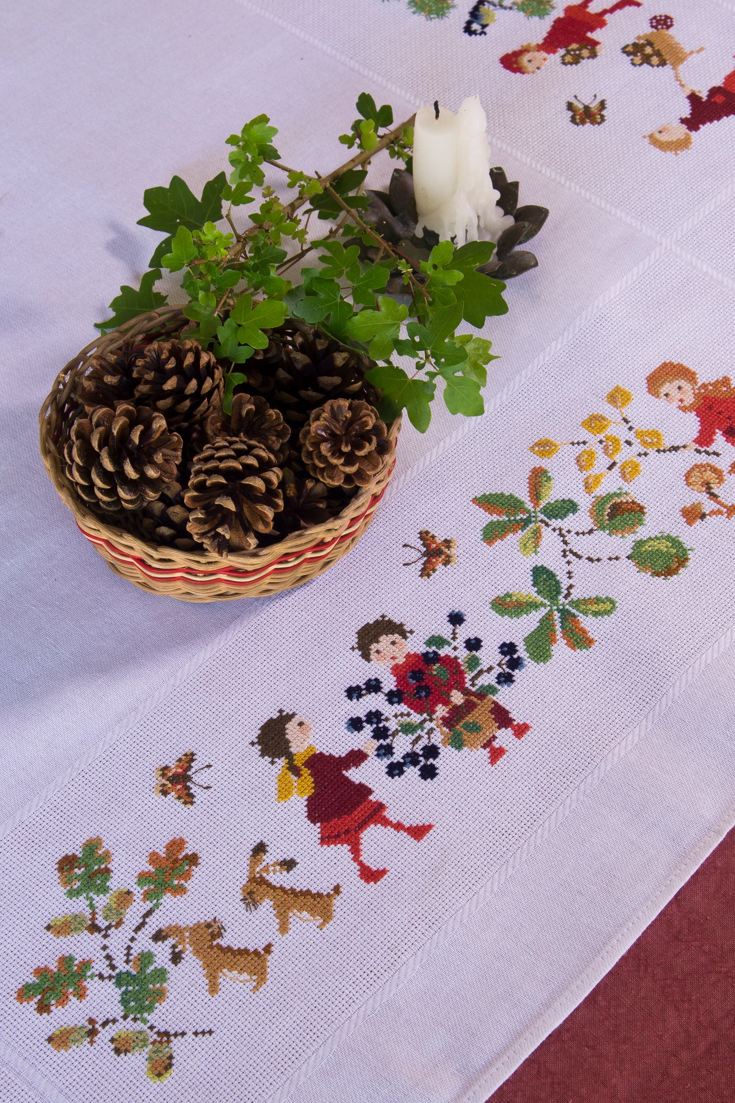 Grille point de croix : nappe d’automne à broder sur toile blanche 5,5 pts. Feuilles, fruits et personnages. 12 pages DMC. Linge de table automnal.