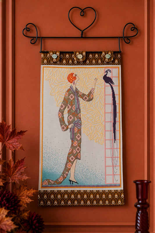 Grille inédite broderie point de croix : La Dame au paon. Silhouette Art déco années folles, paon et feuillage. Toile de lin 12 fils/cm blanc cassé. Réf. DMC, 6 pages.