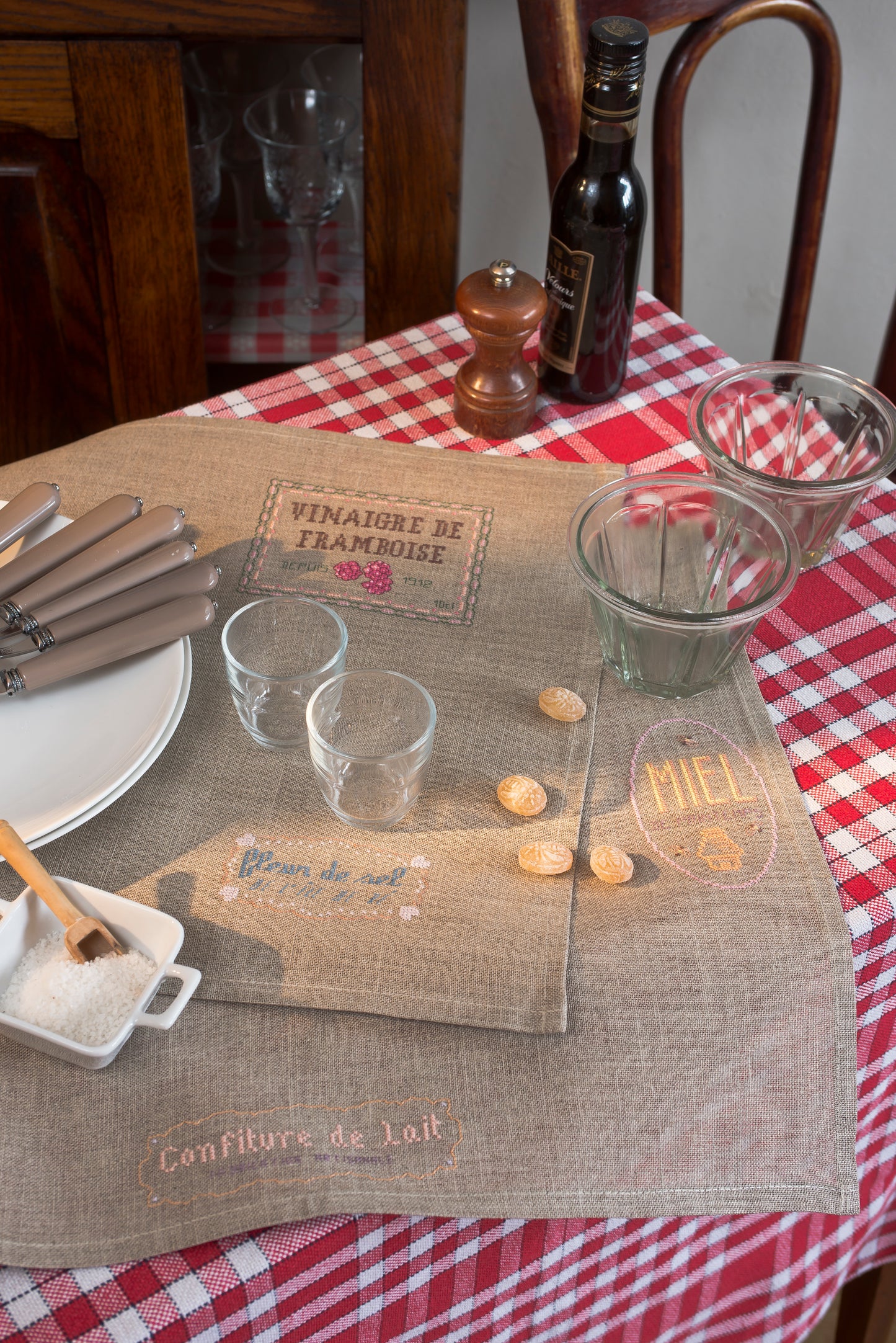 Grille point de croix – Produits du terroir : étiquettes anciennes de spécialités françaises (fleur de sel, confiture, moutarde, confit de canard) brodées sur sets de table en lin thé 12 fils/cm – Monique Bonin & Création Point de Croix
