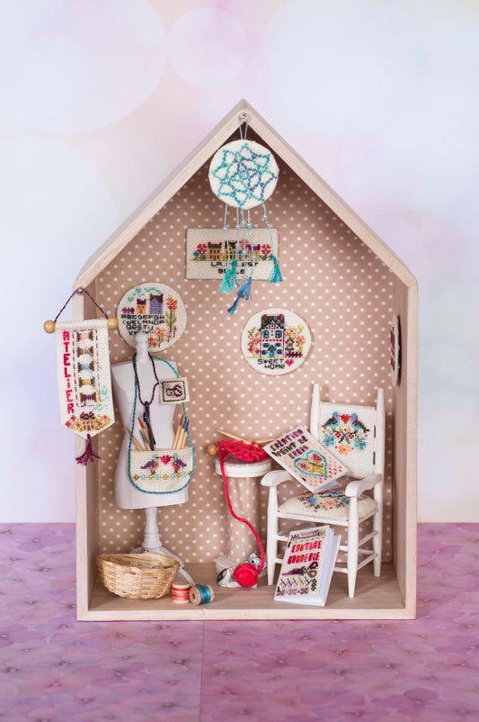 Grille de broderie point de croix : atelier idéal avec mannequin, attrape-rêves, fauteuil et accessoires. Imprimée en couleur avec références DMC sur 8 pages.
