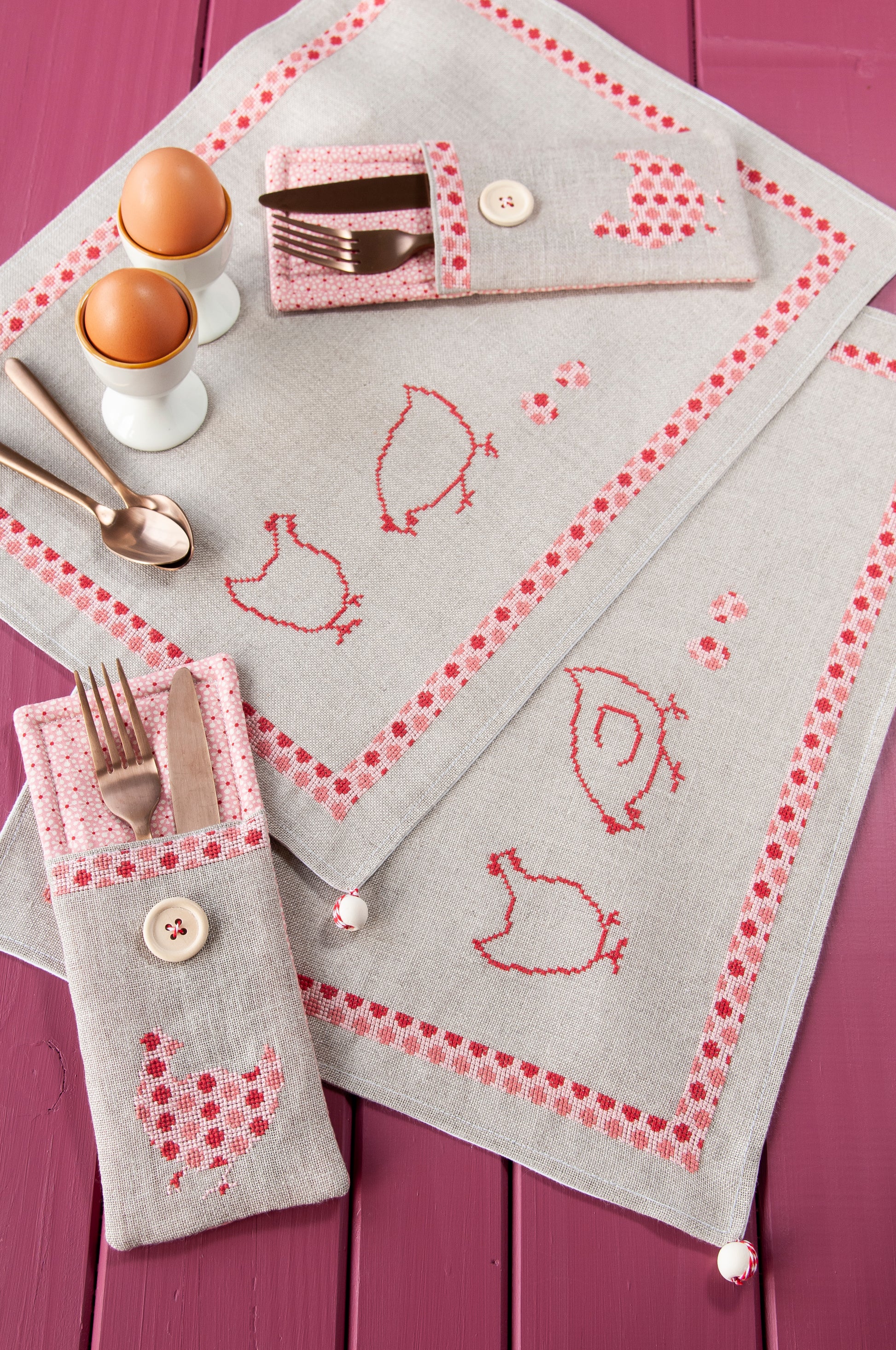 Grille de broderie point de croix « Sets de table poules » : poules à carreaux et à pois sur lin blanc 11 fils. DMC, 10 pages – set de table et pochette à couverts.