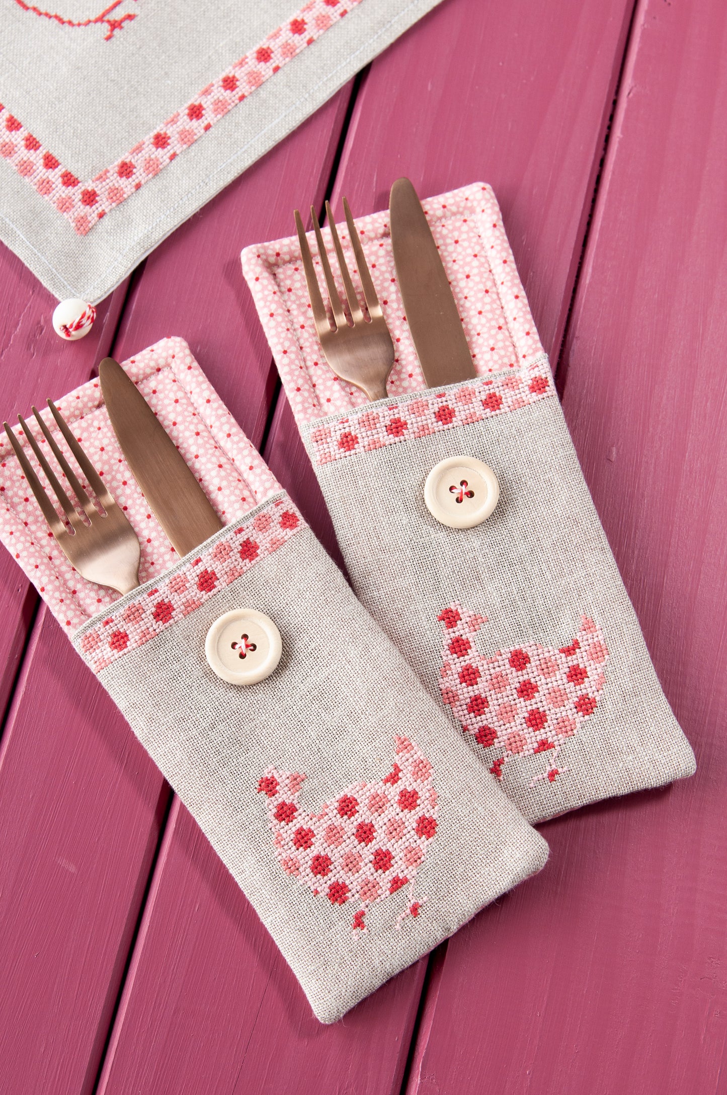 Grille de broderie point de croix « Sets de table poules » : poules à carreaux et à pois sur lin blanc 11 fils. DMC, 10 pages – set de table et pochette à couverts.