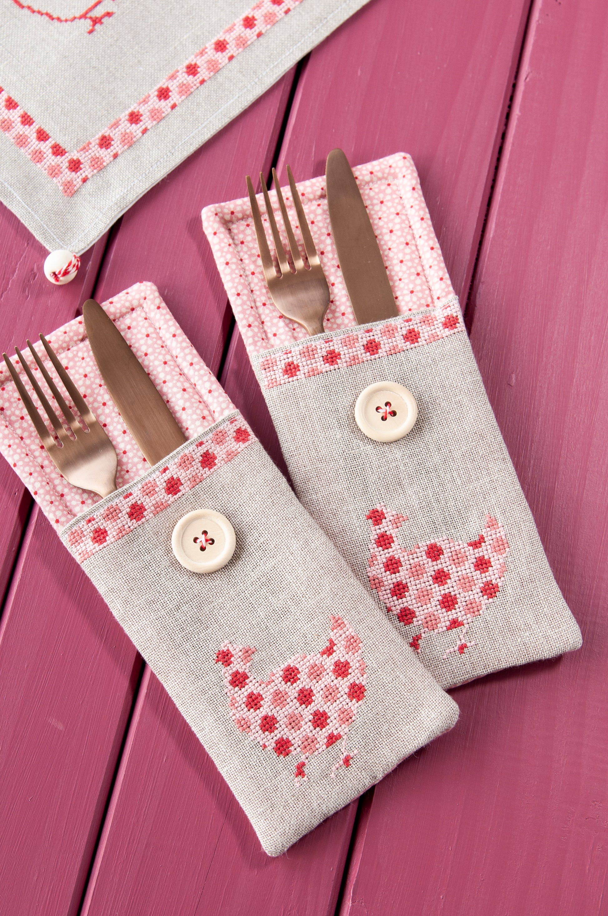 Grille de broderie point de croix « Sets de table poules » : poules à carreaux et à pois sur lin blanc 11 fils. DMC, 10 pages – set de table et pochette à couverts.