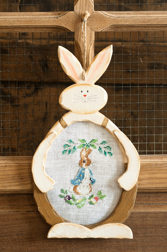 Grille point de croix – Suspension Pierrot-Lapin : Pierrot-Lapin dans le potager du paysan Poupon brodé sur toile de lin DMC B5200 11 fils/cm, présenté dans un cadre en bois découpé en forme de lapin, décoration chambre enfant – Création Point de Croix
