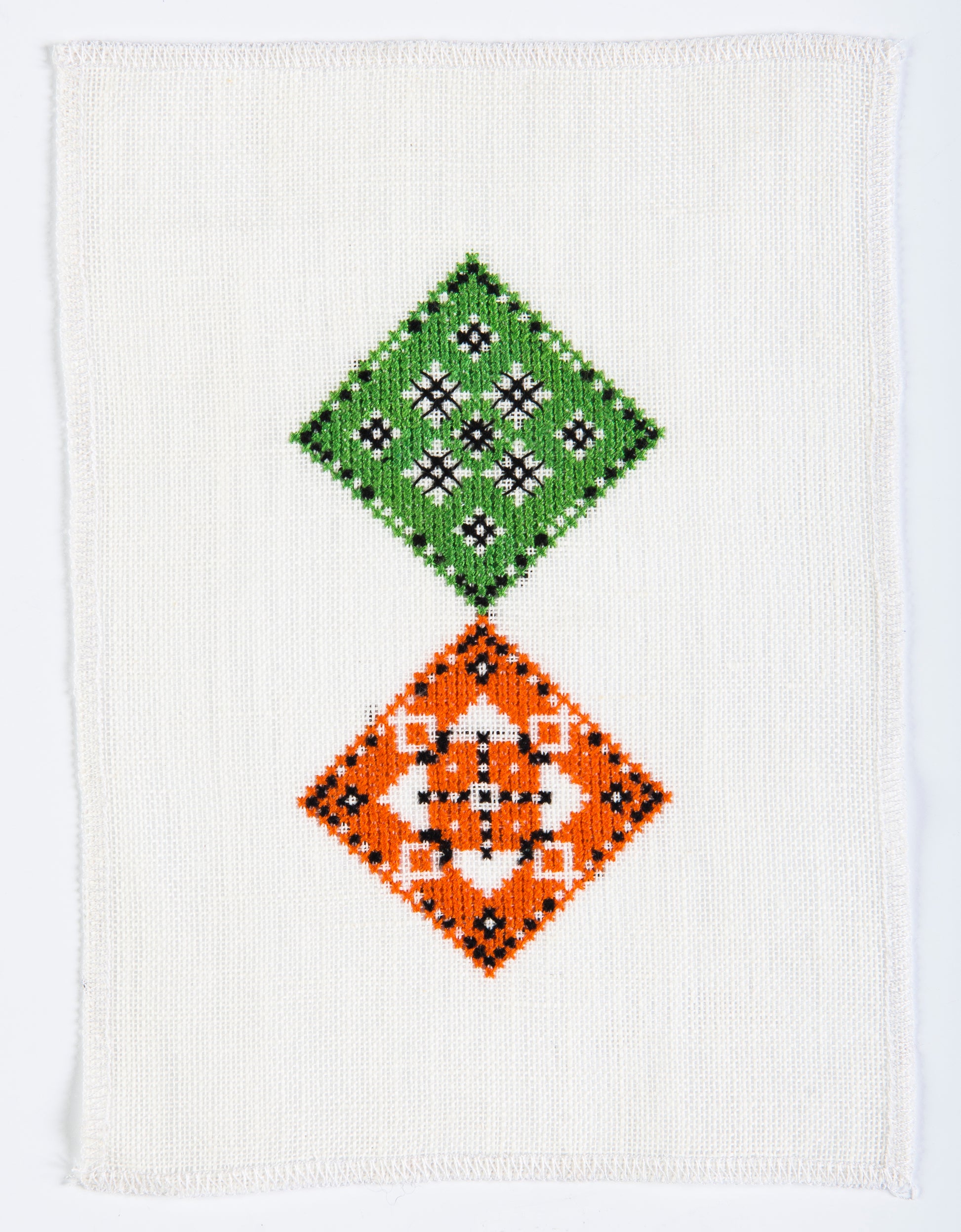 Grille point de croix – Une table au jardin, vue d'ensemble DMC : composition florale et géométrique en relief avec arrosoir, arbuste et gazon miniature sur toile de lin ivoire DMC – Création Point de Croix
