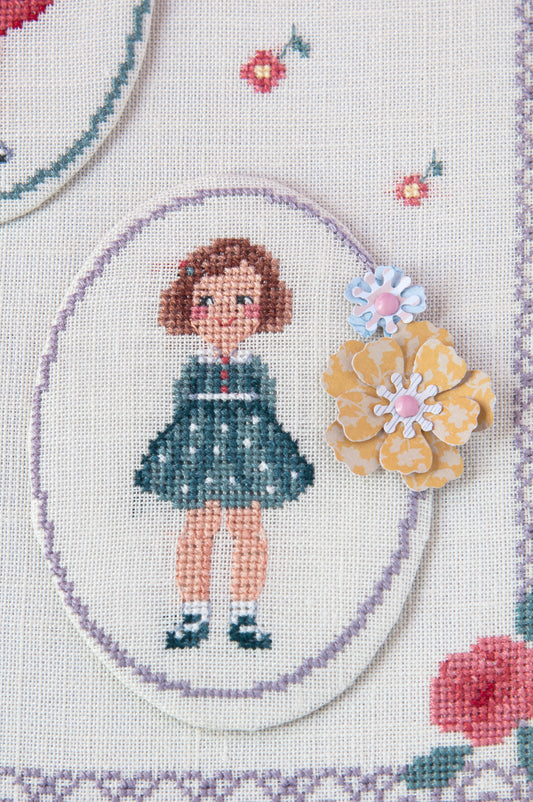 Grille point de croix : petites filles en robes chics dans cadre ovale sur lin clair. Motif 160 x 160 points (29,09 x 29,09 cm), 6 pages, DMC.