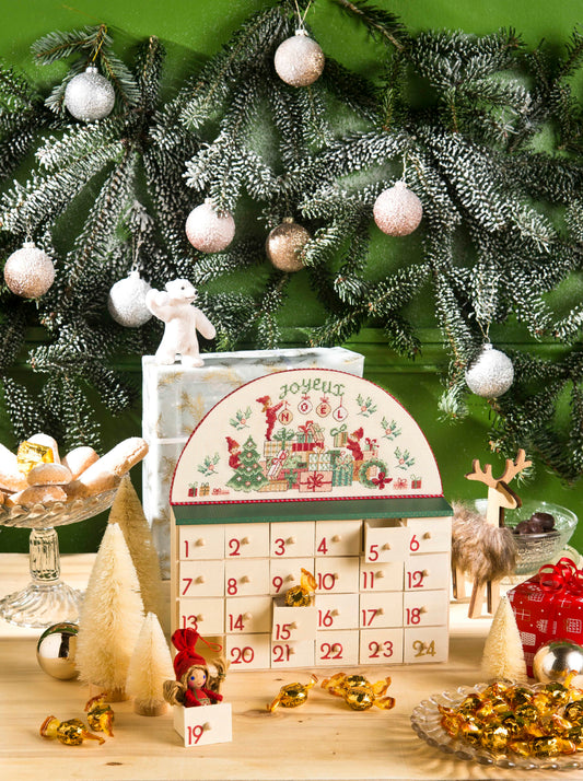 Grille de point de croix Petit meuble calendrier de l'Avent : lutins et sapin sur Aïda 7 pts blanc. 150 x 71 points. Références DMC sur 4 pages.