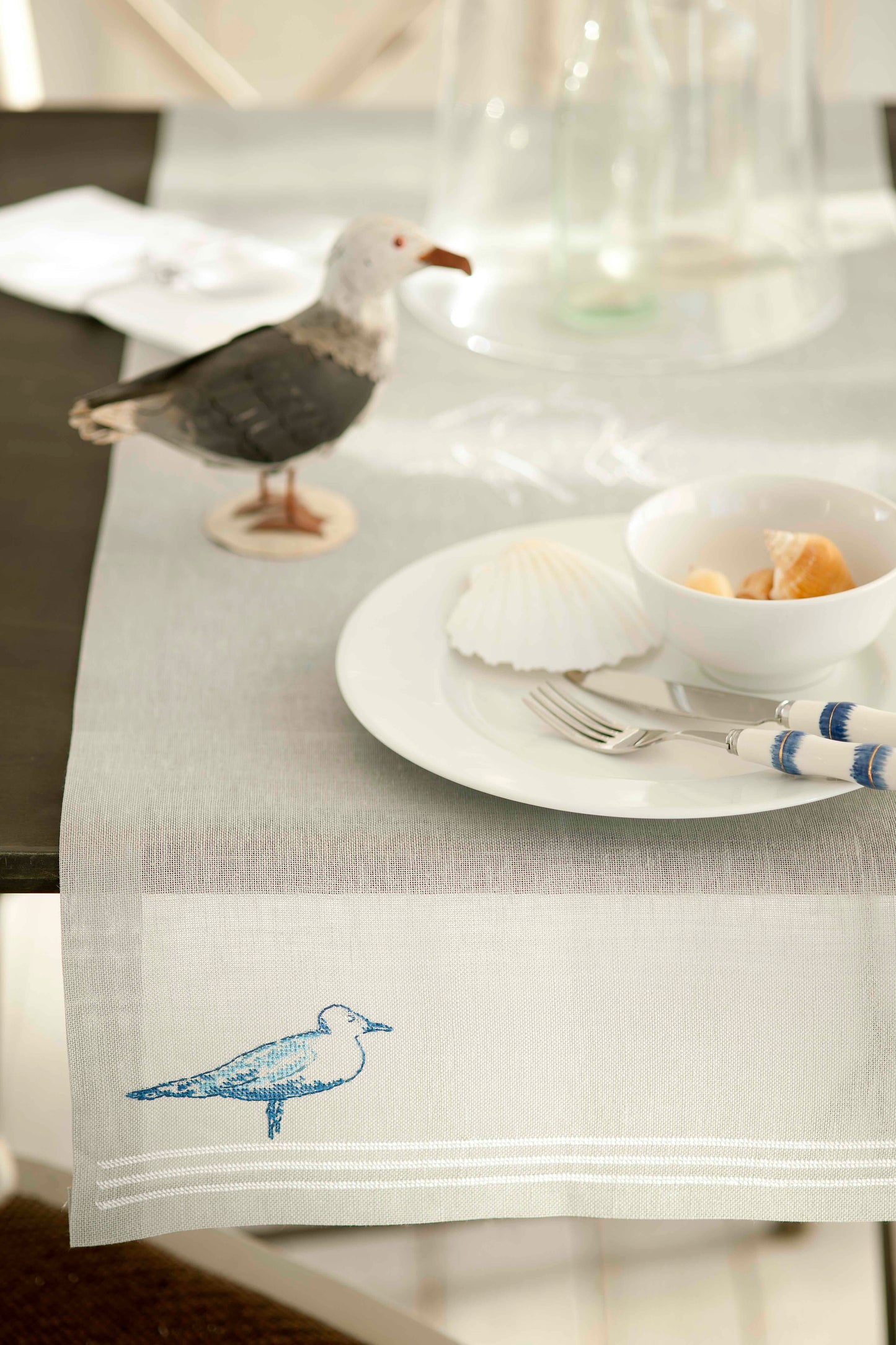 Grille de point de croix Élégance du rivage : mouette et mer sur lin 11 fils gris. Chemin de table et set de table. Références DMC sur 4 pages.