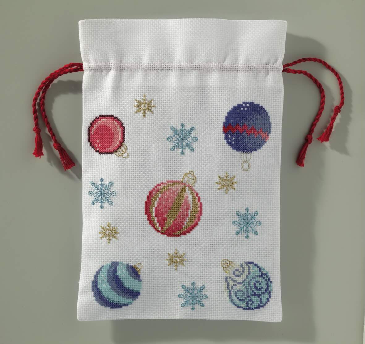 Grille broderie point de croix : nappe de Noël avec boules, flocons et étoiles. Imprimée en couleur sur 6 pages. Réf. DMC incluses.