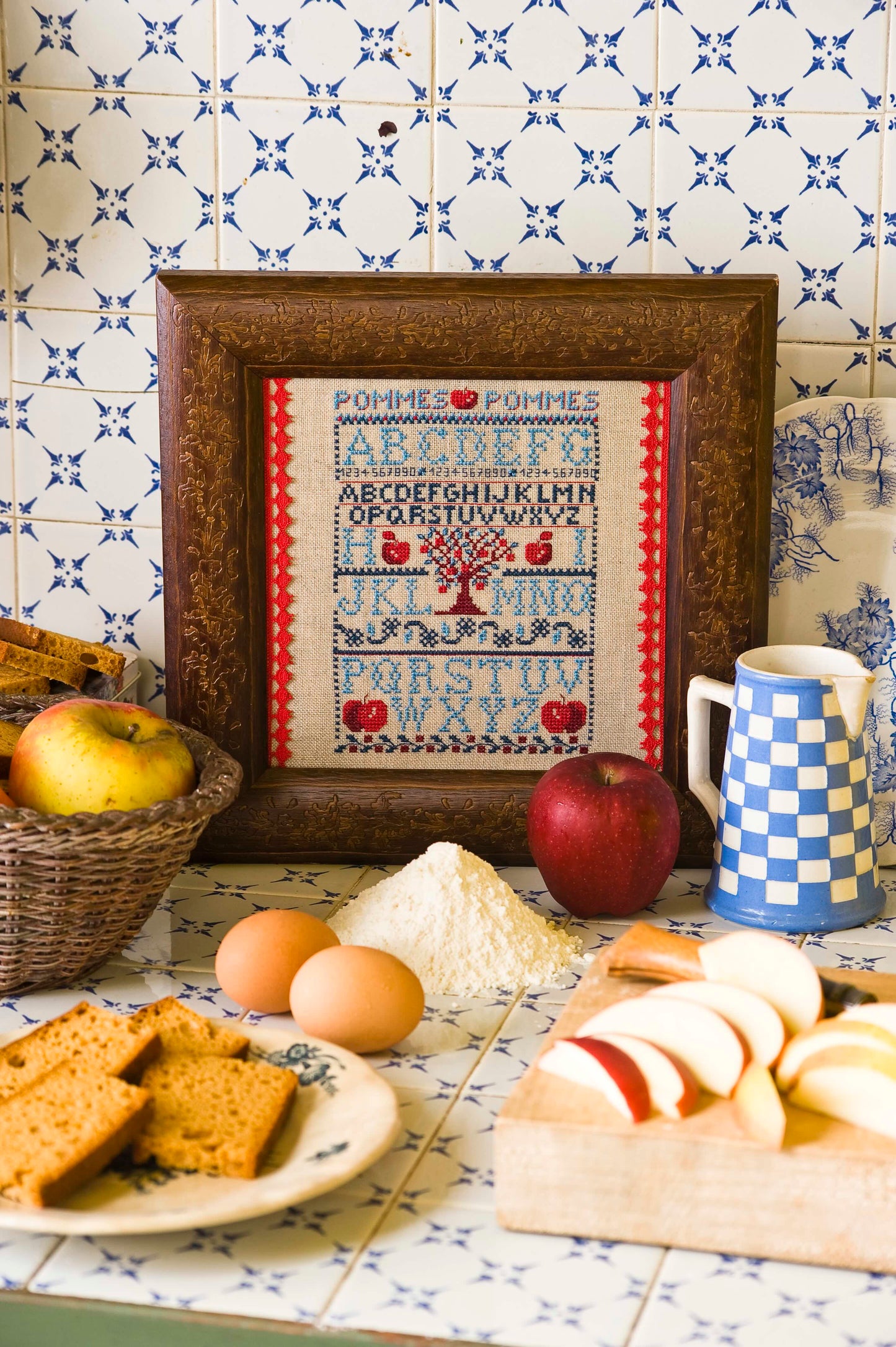 Grille point de croix Sampler Pomme d'Api par Création Point de Croix. Imprimée avec symboles et couleurs DMC, format fini env. 13×18 cm sur lin 12 fils.