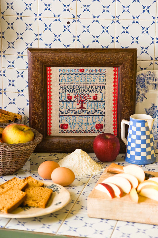 Grille point de croix Sampler Pomme d'Api par Création Point de Croix. Imprimée avec symboles et couleurs DMC, format fini env. 13×18 cm sur lin 12 fils.